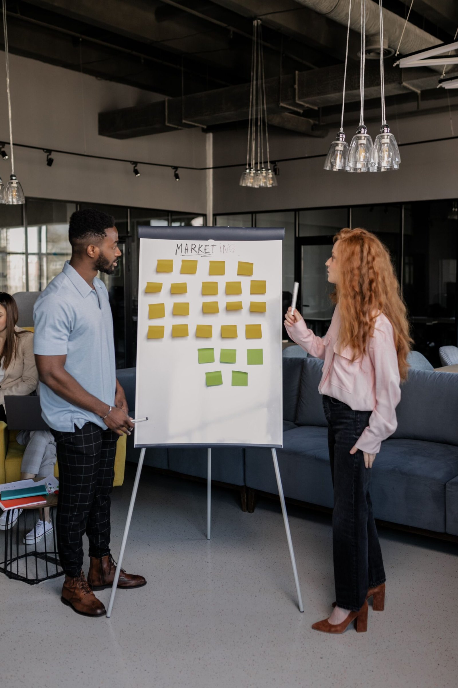 Equipe de agência alinhando briefing com post-its no quadro branco para evitar retrabalho na agência
